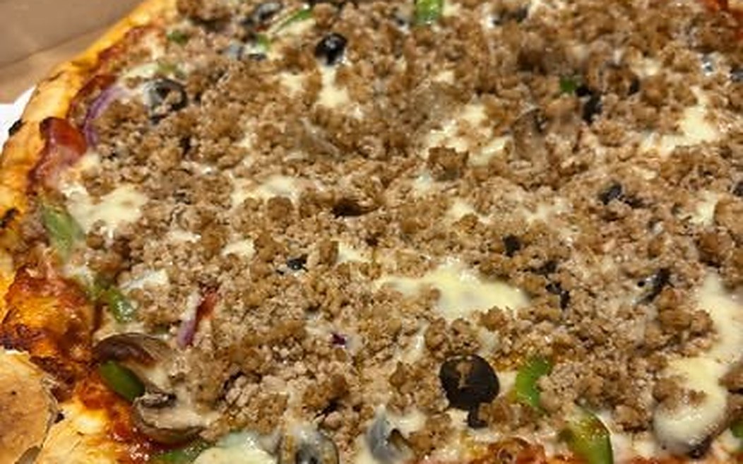 A loaded Pepperoni Bill's pizza in the box, sausage, olives, mushroom and green pepper